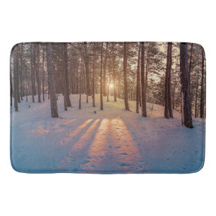 Sonnenuntergang im schneebedeckten Kiefernwald Badematte