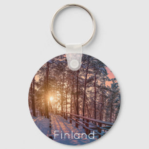 Sonnenuntergang im schneebedeckten Pinienwald mit  Schlüsselanhänger