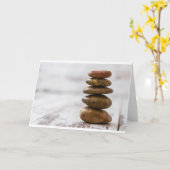 Stapel der Dunkelheit färbte Steine auf weißem Karte (Gelbe Blume)