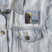 Strohhut, der am Zaun am Strand hängt Button (Beispiel)