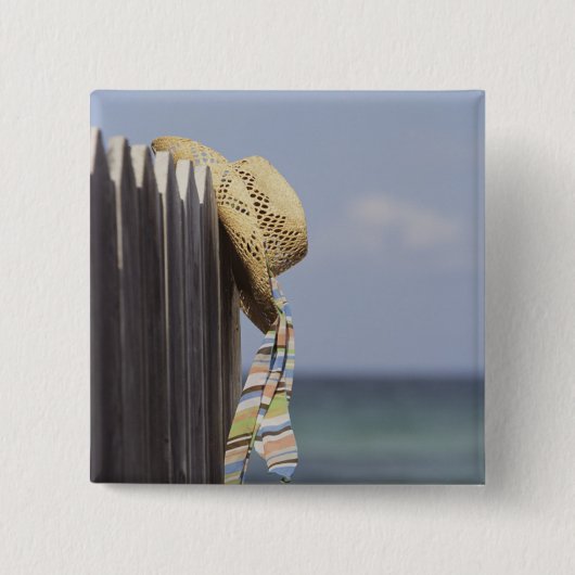 Strohhut, der am Zaun am Strand hängt Button (Vorderseite)
