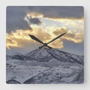 Sturmsonnenuntergang über schneebedeckten Bergen Quadratische Wanduhr