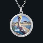 Sun Day Ocean Beach Pier Pelican Bird Foto Niedlic Versilberte Kette<br><div class="desc">"Sonnentag." Dieses niedliche, glückliche Pelikan, das auf einem Geländer über einem kalifornischen Strand steht, schreit nach "Urlaub bereit". Lassen Sie sich von den warmen Meeresbrisen abhalten, wenn Sie diese farbenfrohe, fotografische Charme-Halskette tragen. Diese Halskette ist in kleinen, mittleren und großen Größen sowie in quadratischer und kreisförmiger Form erhältlich. Sie können...</div>