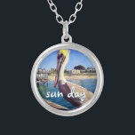 Sun Day Ocean Beach Pier Pelican Bird Foto Niedlic Versilberte Kette<br><div class="desc">"Sonnentag." Dieses niedliche, glückliche Pelikan, das auf einem Geländer über einem kalifornischen Strand steht, schreit nach "Urlaub bereit". Lassen Sie sich von den warmen Meeresbrisen abhalten, wenn Sie diese farbenfrohe, fotografische Charme-Halskette tragen. Diese Halskette ist in kleinen, mittleren und großen Größen sowie in quadratischer und kreisförmiger Form erhältlich. Sie können...</div>