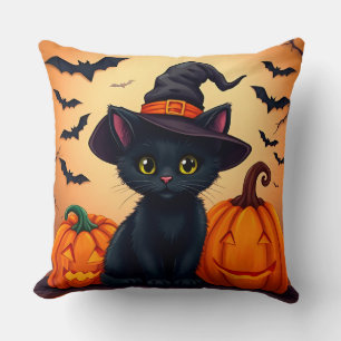 Süße schwarze Katze in einem Hexenhut, umgeben von Kissen