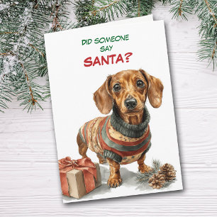 Süßer brauner Dachshund sucht nach dem Weihnachtsm Feiertagskarte