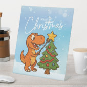 Süßer Dinosaurier mit Weihnachtsbaum Sockelschild (In Situ)