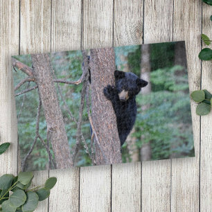 Süßer schwarzer Bärenjunge klettert auf einen Baum Puzzle