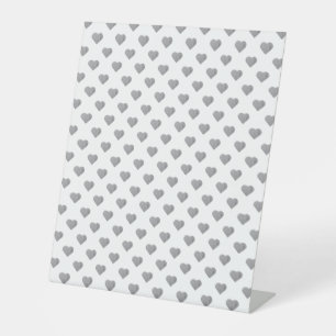 Symmetrische kleine Betonherzen auf Weiß Sockelschild