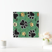 Tan und schwarze Pfote auf grünem Gras Quadratische Wanduhr (Zuhause)