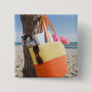 Tasche, die am Baum-Stamm an Sandy-Strand hängt Button