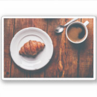 Tasse Kaffee und Croissant am rustikalen Tisch