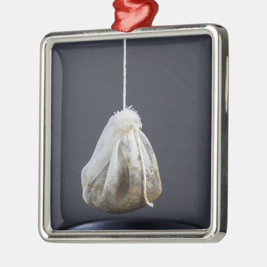 Teebeutel hängt in einer Tasse Silbernes Ornament (Links)