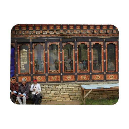Three men sit on a bench at the Memorial Chorten Magnet (Horizontal)