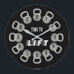 Time to Lift Kettlebell Wall Clock Große Wanduhr<br><div class="desc">This bold Time to Lift wall clock features twelve kettlebells arranged around the dial, each displaying a number for a unique and powerful fitness-inspired design. Set on a sleek black background with gray kettlebells and clean black clock hands, this minimalist piece captures the strong aesthetic of modern gym spaces. The...</div>