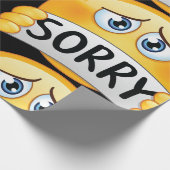 Trauriges Sorry Emoji Gesicht hält Entschuldigungs Geschenkpapier (Ecke)