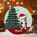 Tricolor Corgi Weihnachtsmannmütze Personalisiert  Keramik Ornament<br><div class="desc">Dieser wunderschöne Pembroke Walisisch Corgi Hund hat einen niedlichen Hut des Weihnachtsmanns und eine bezaubernde Kopfneigung. Der dreiseitige Jungtier sitzt vor einem hübschen Weihnachtsbaum,  der mit bunten Ornamenten geschmückt ist. Personalisieren Sie den Namen Ihres Haustieres in einem hübschen Kursiv unter dem wunderbaren zeichn meines Lieblingshündchens.</div>
