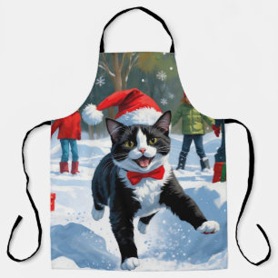 Tuxedo-Katze läuft im Schnee mit Weihnachtsmütze Schürze