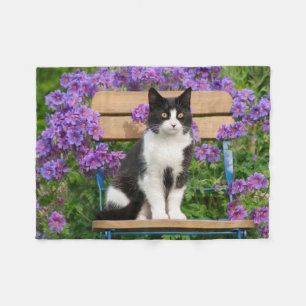 Tuxedo Katze sitzt auf einem Gartenstuhl mit Blume Fleecedecke