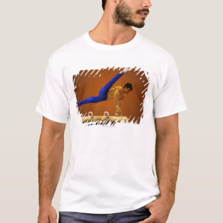 Übende Gymnastik des jungen Mannes auf dem Knauf T-Shirt