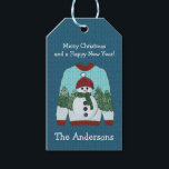 Ugly Christmas Sweater | Niedlich Snowman Geschenkanhänger<br><div class="desc">Das Design zeichnet sich durch einen wirklich niedlichen, hässlichen Pullover aus, mit einem Schneemann mit grünem Schal und einer roten Mütze auf einem schneebedeckten Kiefernwald. Blau gestrickter Wollhintergrund. Individuell gestaltbare Urlaubsnachrichten und personalisieren mit Namen oder Familienname. Karo in der Ugly Sweater Kollektion für mehr Spaß beim Dekorieren von Party, Party,...</div>