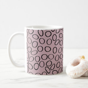 Unregelmäßiges schwarzes Zirkelmuster auf rosa Kaffeetasse