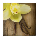 Vanille-Hülsen und Blume über hölzernem Fliese (Vorderseite)