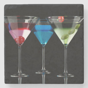 Verschiedene Cocktails in Martini-Brillen auf schw Steinuntersetzer