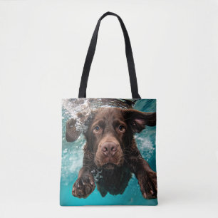 Verspielter Chocolate-Labrador schwimmt unter Wass Tasche