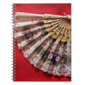 Verzierter Handheld-Lüfter auf einem roten Hinterg Notizblock (Vorderseite)