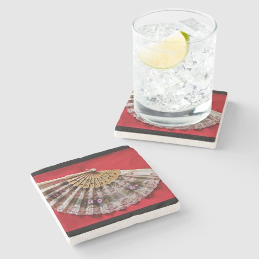 Verzierter Handheld-Lüfter auf einem roten Hinterg Steinuntersetzer (Seitenansicht)