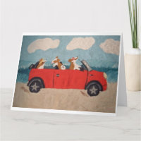 Walisische Corgis in einem roten Cabrio am Strand