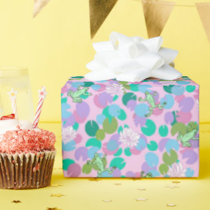 Weibliche grüne Frösche und Lilienpads auf rosa Geschenkpapier