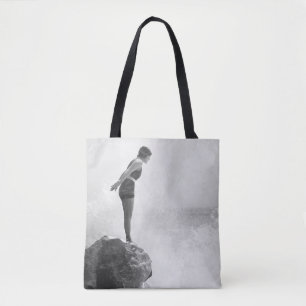 Weibliche Schwimmerin auf Felsen über dem abstürze Tasche