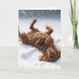 Weihnachts-Irish-Setter macht einen Schneengel Feiertagskarte