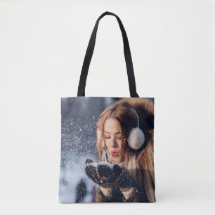 Weihnachts-Wintermädchen bläst in ihrer Hand Schne Tasche