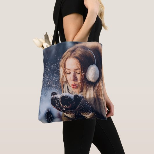 Weihnachts-Wintermädchen bläst in ihrer Hand Schne Tasche (Von Nahem)