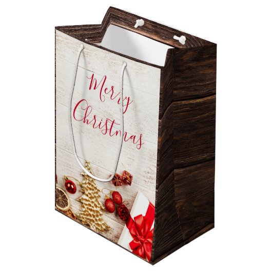 Weihnachtsgeschenkartikel auf einem rustikalen Hol Mittlere Geschenktüte (Vorderseite Schrägansicht)