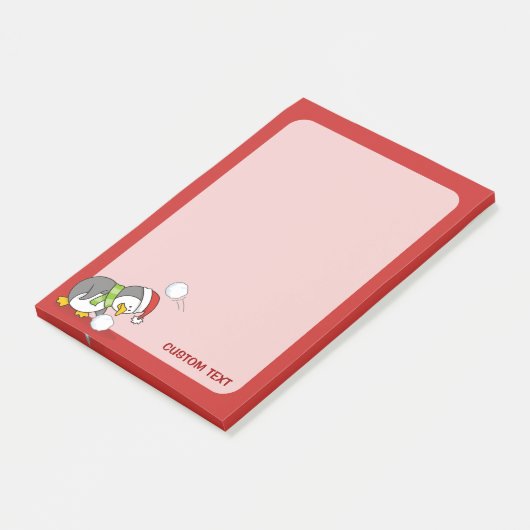 Weihnachtspinguin bekommt eine Schneeball Post-it Klebezettel (angewinkelt)