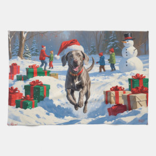Weimaraner läuft im Schnee mit Weihnachtshut Geschirrtuch