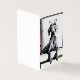 Weimaraner mit einer Krone auf einem Stuhl sitzend