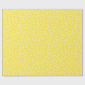 Weiße Confetti-Sprinklen auf hellgelben Geschenkpapier (Flach)
