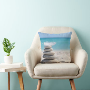 Weiße Feder auf einem Strandsteinhaufen Kissen