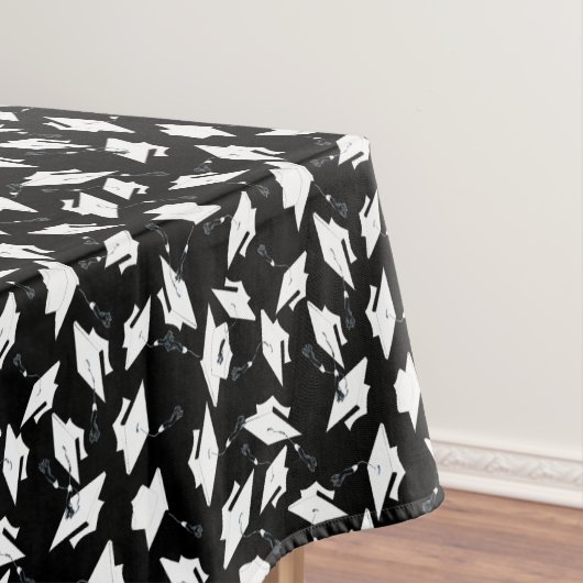 Weiße Graduierungskappen in die Luft geworfen auf Tischdecke (Beispiel)