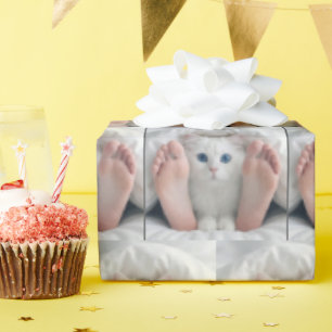 Weiße Katze und menschliche Füße unter einer Decke Geschenkpapier
