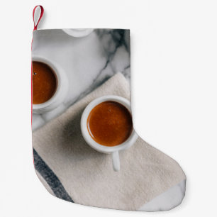 WEIßE KERAMIK-TEETASSE GEFÜLLT MIT ROTER FLÜSSIGKE KLEINER WEIHNACHTSSTRUMPF