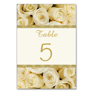 Weiße SahneRosen mit einem Gold färbten Tischnummer