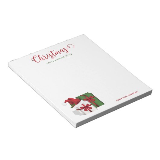 Weiße und grüne Geschenkboxen mit Weihnachtsmannmü Notizblock (angewinkelt)
