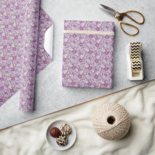 Weiße und violette Blumen auf einem helllila Hinte Geschenkpapier