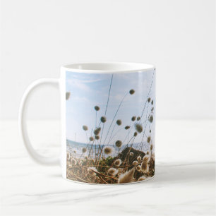 WEIßES BLUMENFELD NAHE EINEM GEWÄSSER UNTER BLAUEM KAFFEETASSE